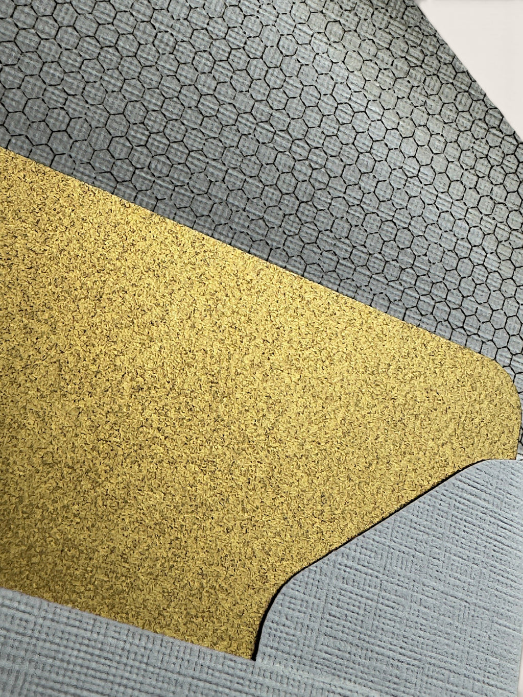 A close-up of a textured material sample with three distinct sections: a large central gold glitter section, a gray honeycomb-patterned section at the top, and a light blue-gray ribbed section at the bottom.