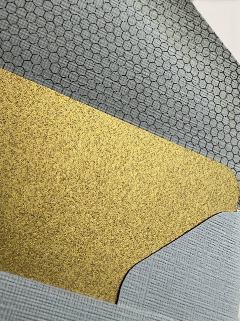 A close-up of a textured material sample with three distinct sections: a large central gold glitter section, a gray honeycomb-patterned section at the top, and a light blue-gray ribbed section at the bottom.