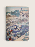 A hardcover notebook featuring a classic Japanese ukiyo-e woodblock print of a river scene with figures, boats, and buildings, shown against a light beige background.