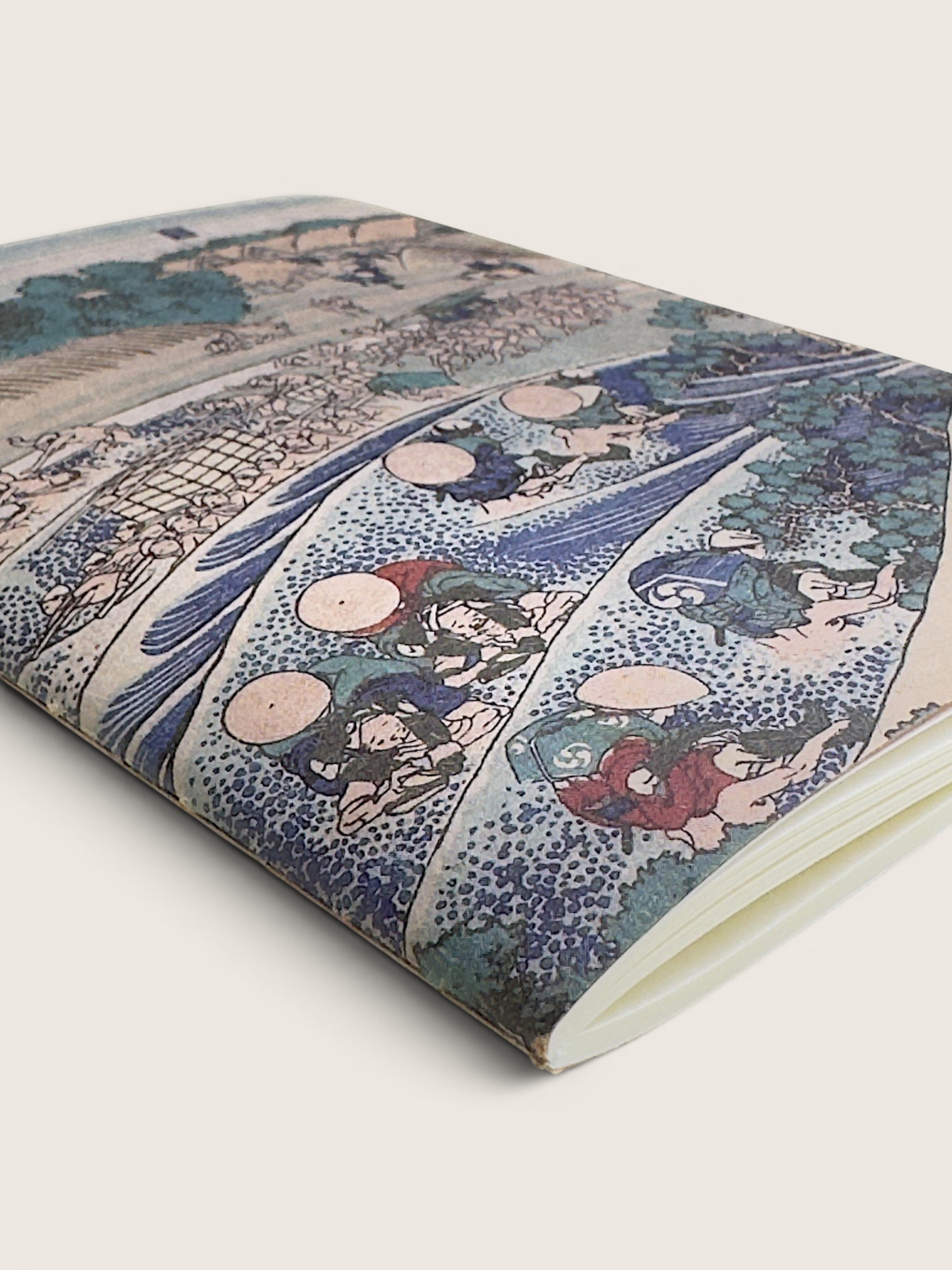 A notebook or journal featuring a detailed Japanese ukiyo-e woodblock print cover, shown at an angle on a light beige background.