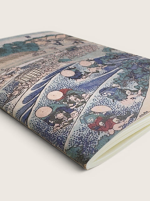 A notebook or journal featuring a detailed Japanese ukiyo-e woodblock print cover, shown at an angle on a light beige background.