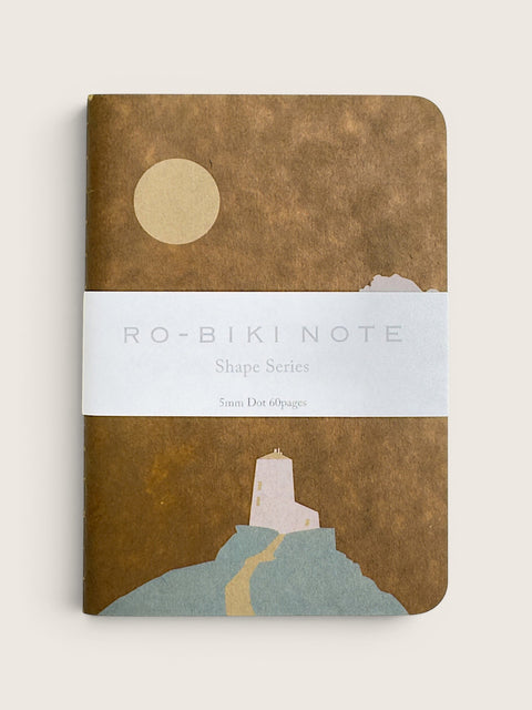 A notebook with a textured brown cover featuring a minimalist illustration of a lighthouse, a winding path, and a pale yellow sun. A white paper band across the center reads 'RO-BIKI NOTE Shape Series'.