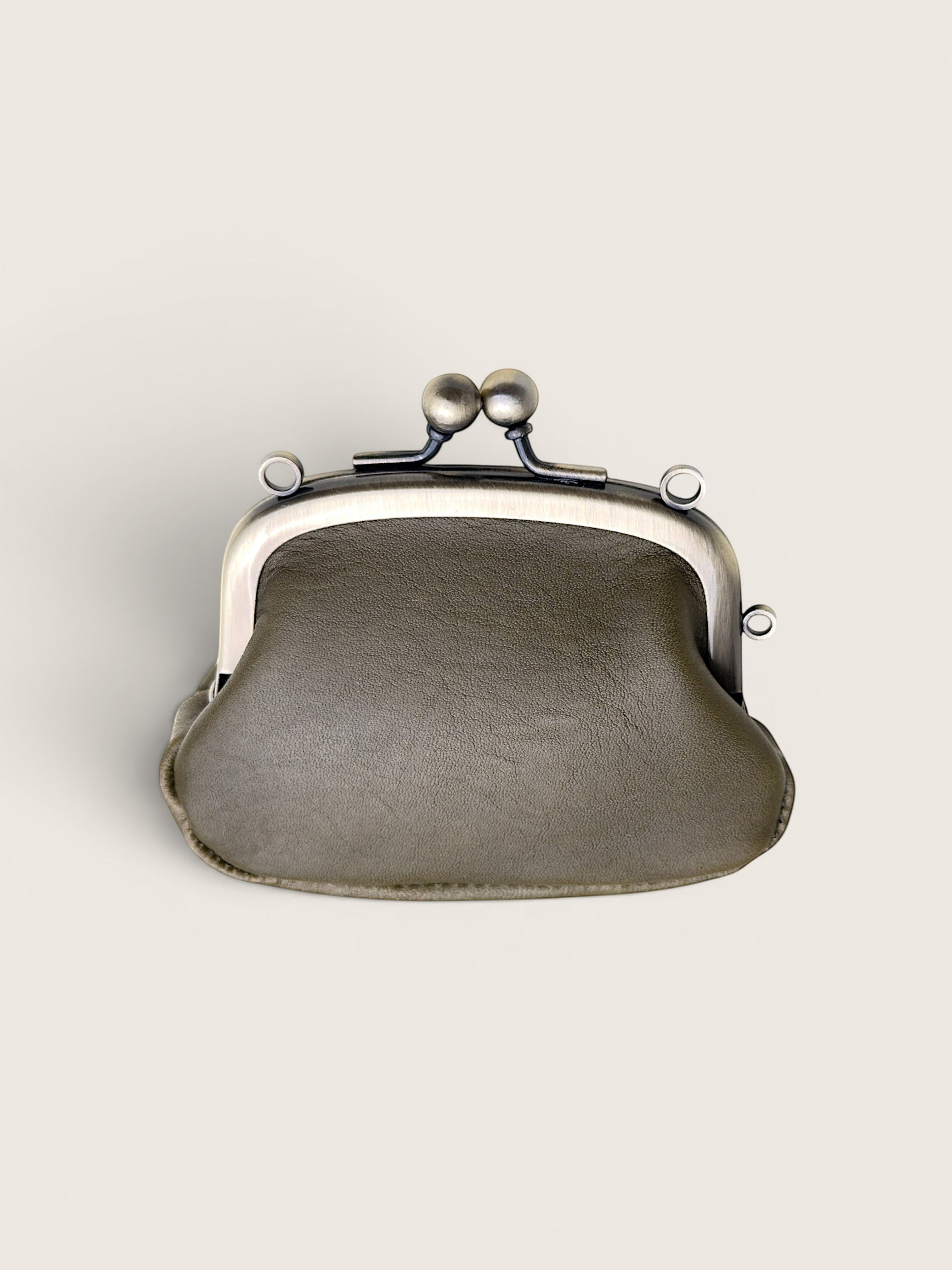 A small kiss-lock clutch bag in textured taupe leather with a silver-tone metal frame and clasp, shown against a solid off-white background.