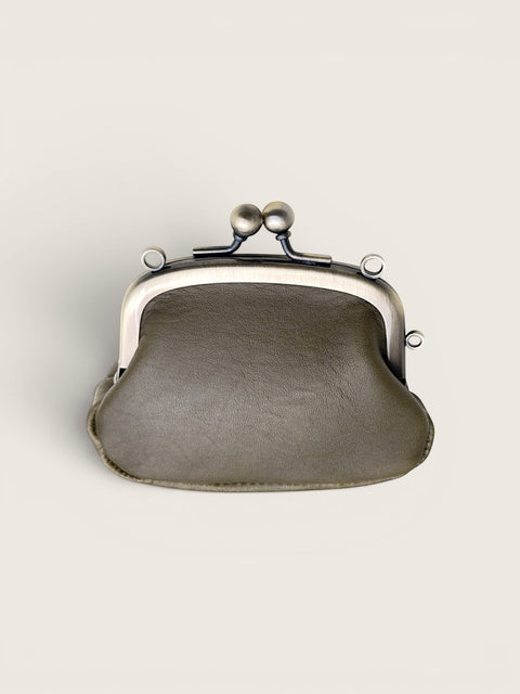 A small kiss-lock clutch bag in textured taupe leather with a silver-tone metal frame and clasp, shown against a solid off-white background.