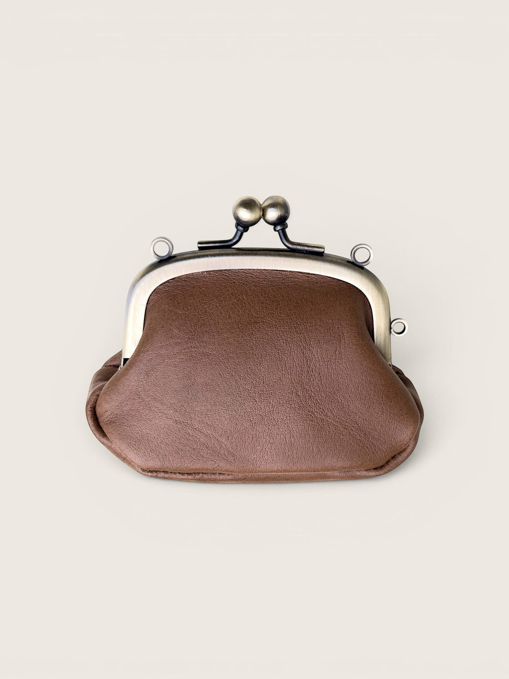 A brown faux-leather kiss-lock clutch purse with a silver-tone metal frame and black spring clasp, shown on a light beige background.
