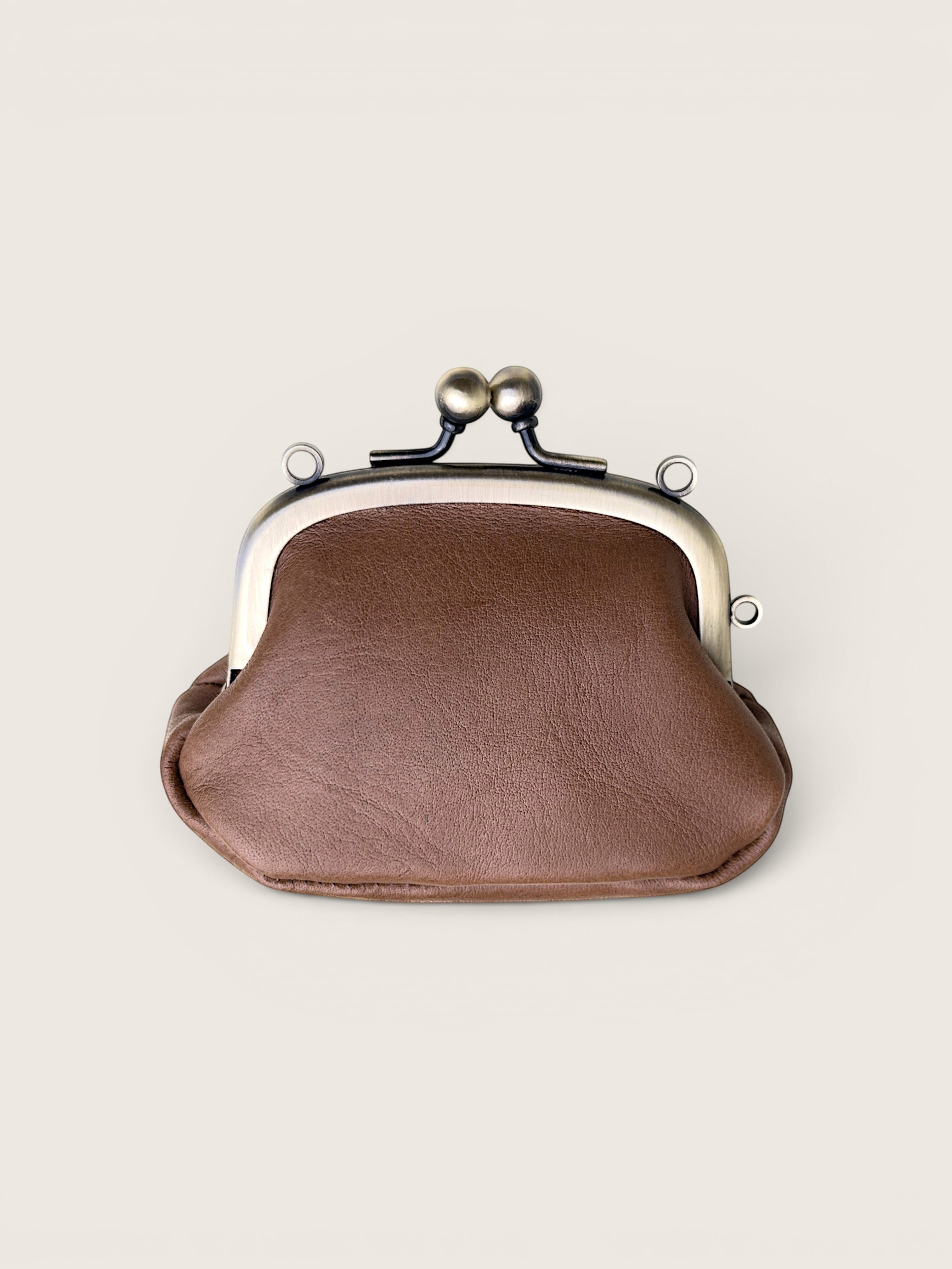 A brown faux-leather kiss-lock clutch purse with a silver-tone metal frame and black spring clasp, shown on a light beige background.
