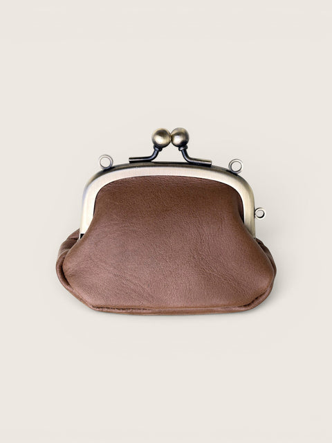 A brown faux-leather kiss-lock clutch purse with a silver-tone metal frame and black spring clasp, shown on a light beige background.
