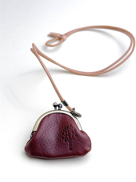 A small burgundy leather kiss-lock coin purse with a matching tan leather shoulder strap, displayed on a clean white background.