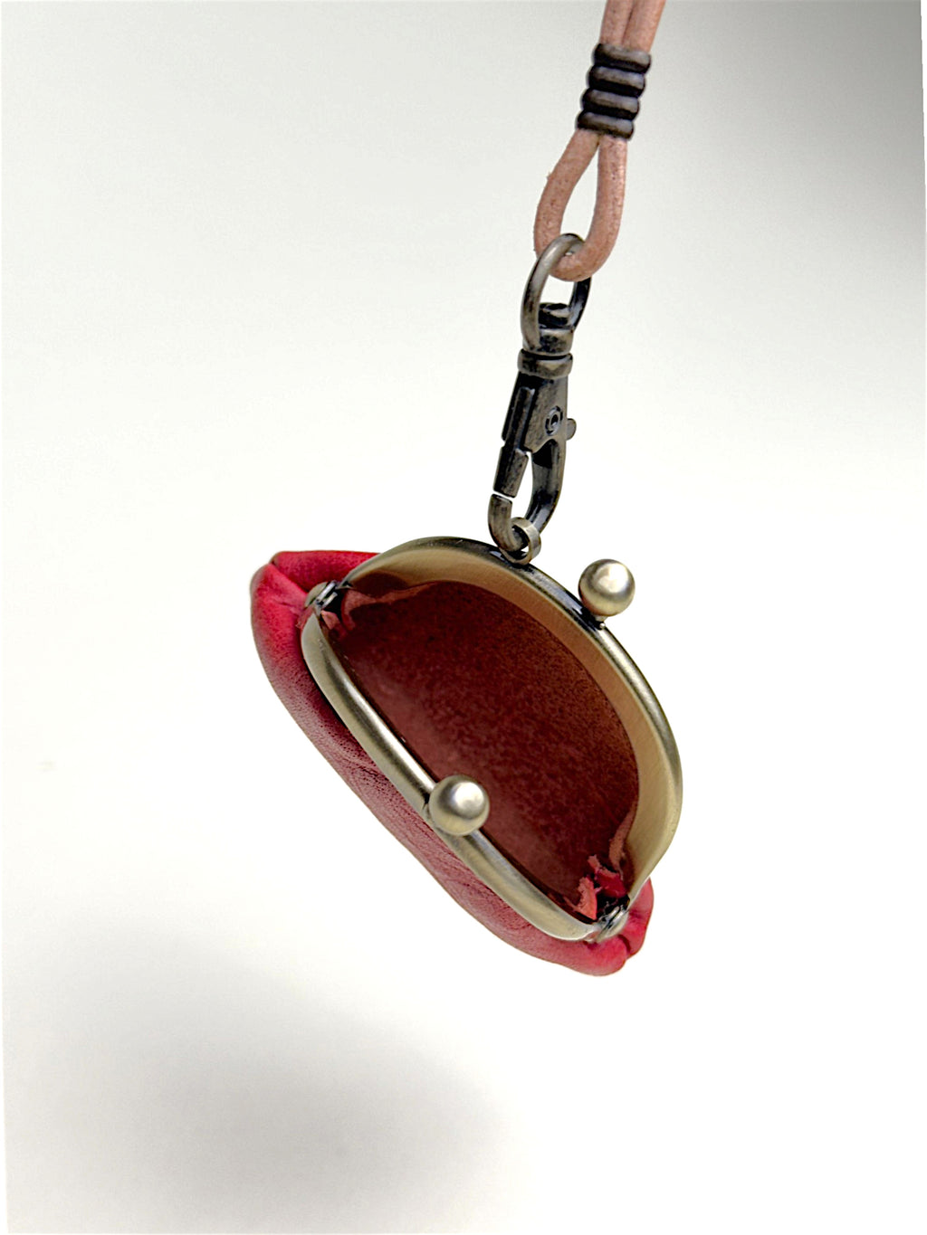 A small red velvet kiss-lock coin purse with a silver-tone metal frame and pearl-like snap buttons, attached to a black lobster clasp and a light pink woven strap, shown against a plain white background.