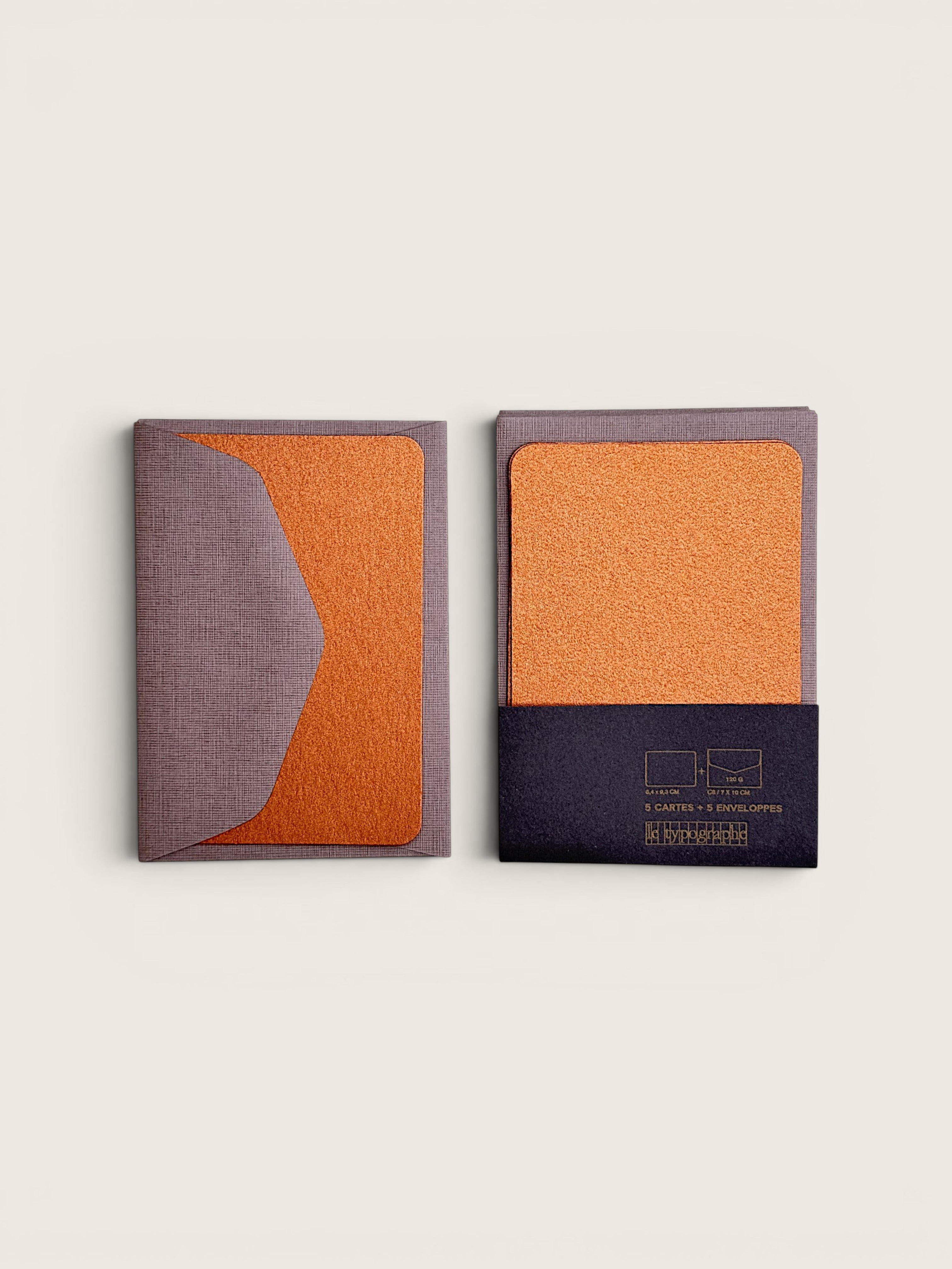 Two slim rectangular card holders or passport covers shown on a light warm gray background. One is closed, showing a curved split design in muted taupe and textured orange.