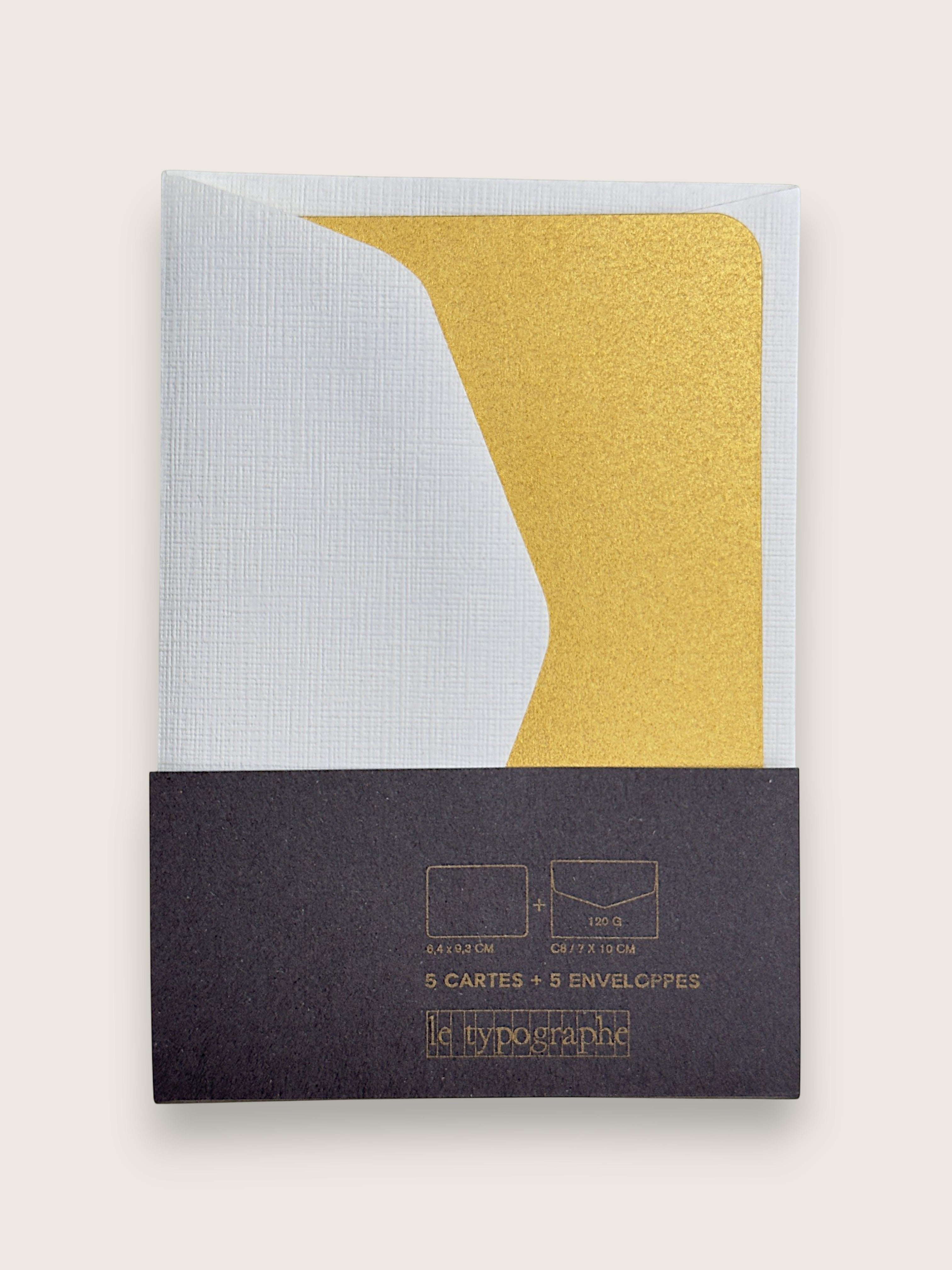 A set of 5 paper envelopes by le typographe, featuring a white textured envelope, a gold glitter envelope, and a dark charcoal gray paper sleeve packaging with gold foil text.