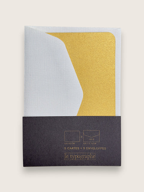 A set of 5 paper envelopes by le typographe, featuring a white textured envelope, a gold glitter envelope, and a dark charcoal gray paper sleeve packaging with gold foil text.