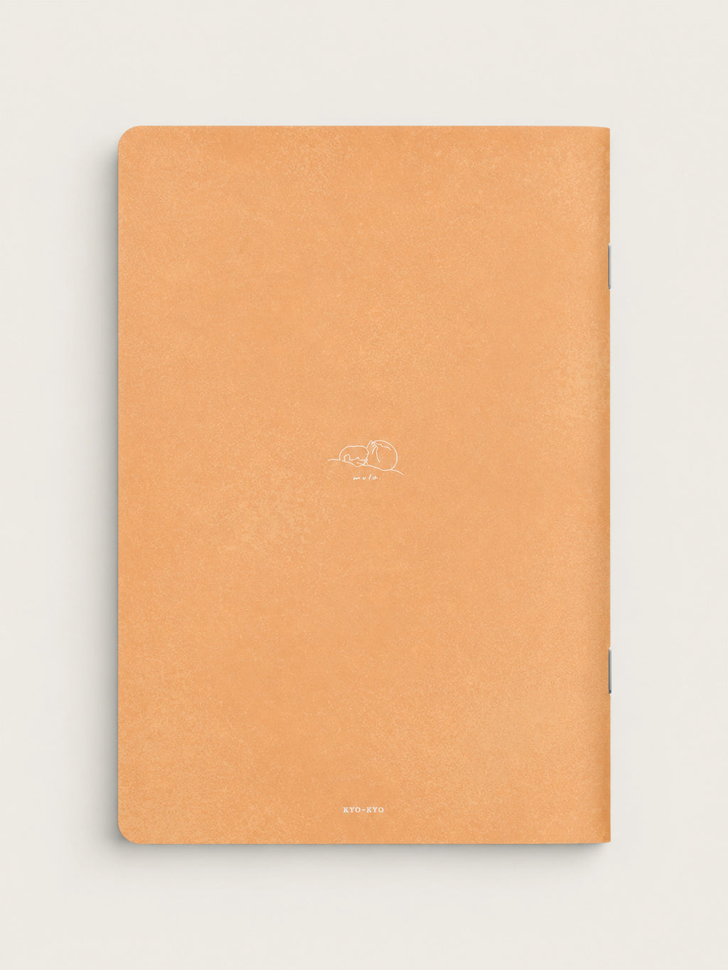 A peach-colored textured notebook with a minimalist white line drawing of a sleeping dog and the word 'dream' on the cover, shown against a light off-white background.