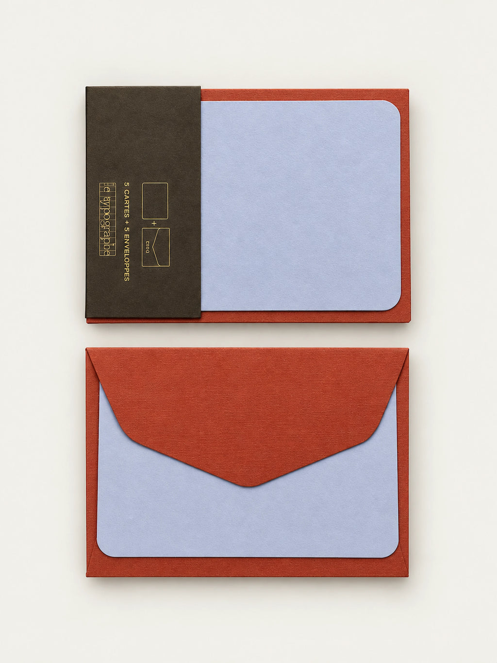 Lavender letterpress note card held in its charcoal paper band against a cordyline envelope, shown above a second envelope with a card behind the flap.