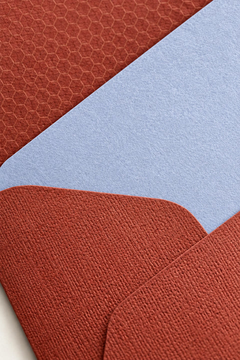 Close detail of a lavender card against a cordyline envelope, showing the honeycomb pattern printed inside the envelope.