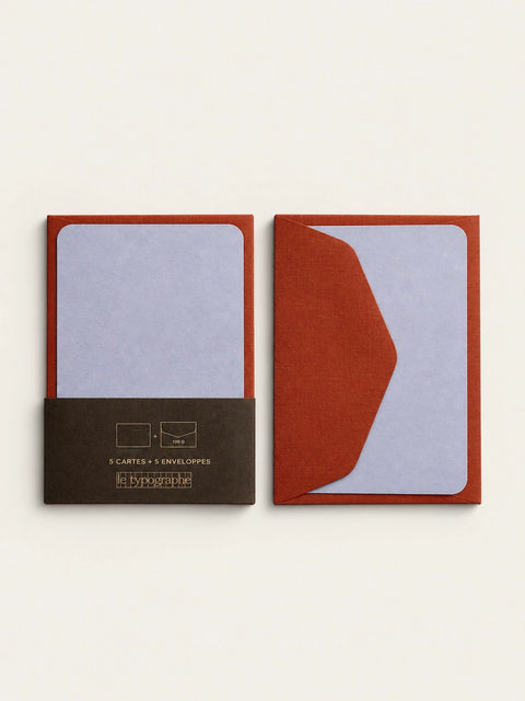 Two lavender mini note cards side by side, one in the printed charcoal band and one tucked behind a cordyline envelope flap.