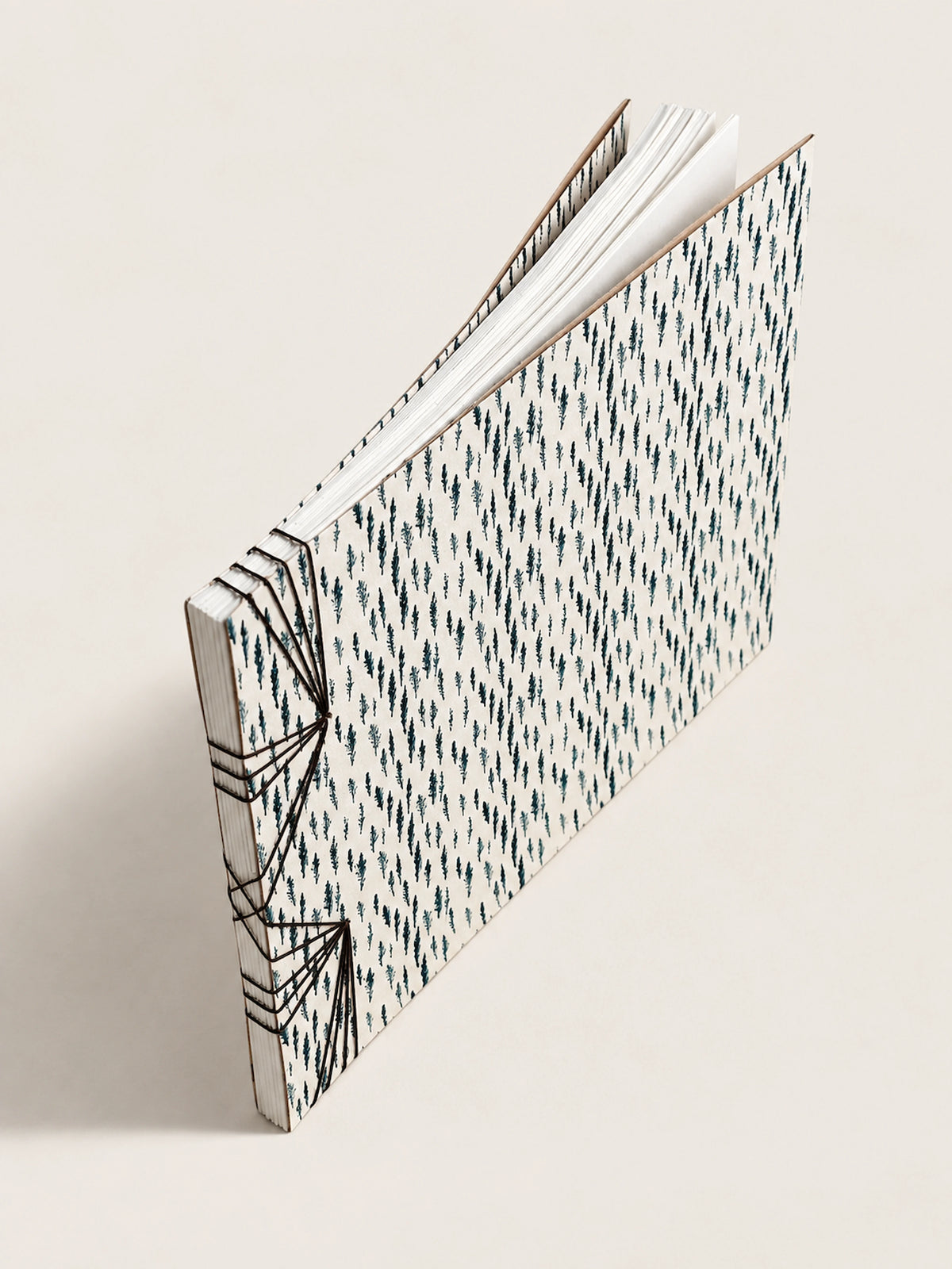 A handmade french notebook with a black and white geometric patterned cover, standing open at an angle on a light beige background.