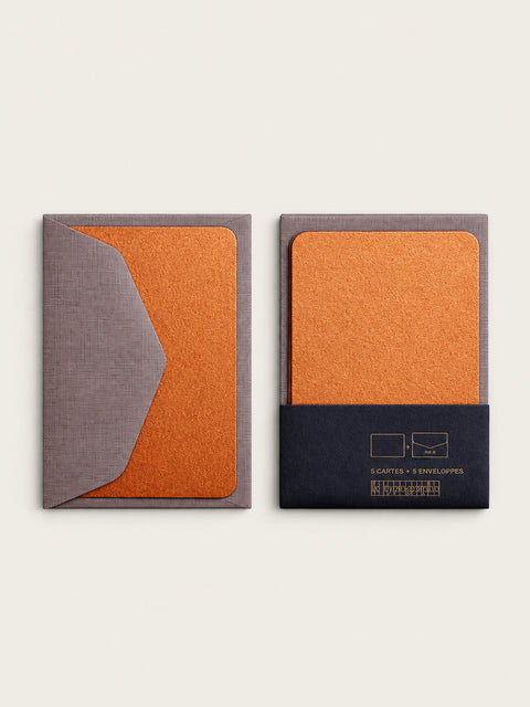 Two copper mini note cards side by side, one behind its barley envelope flap and one in the charcoal band printed 5 cartes and 5 enveloppes.