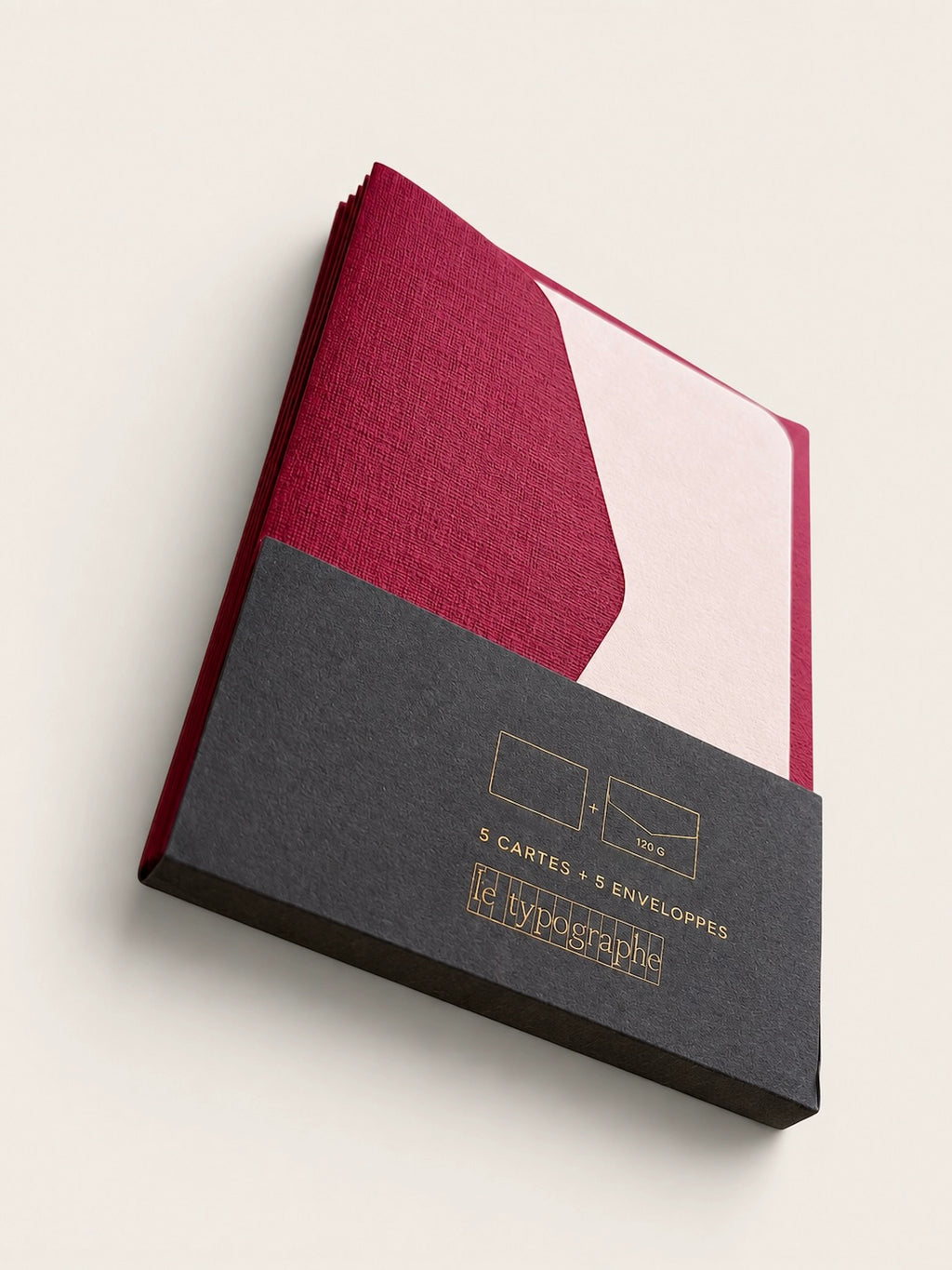 Angled view of Le Typographe burgundy and peach mini cards in charcoal paper sleeve