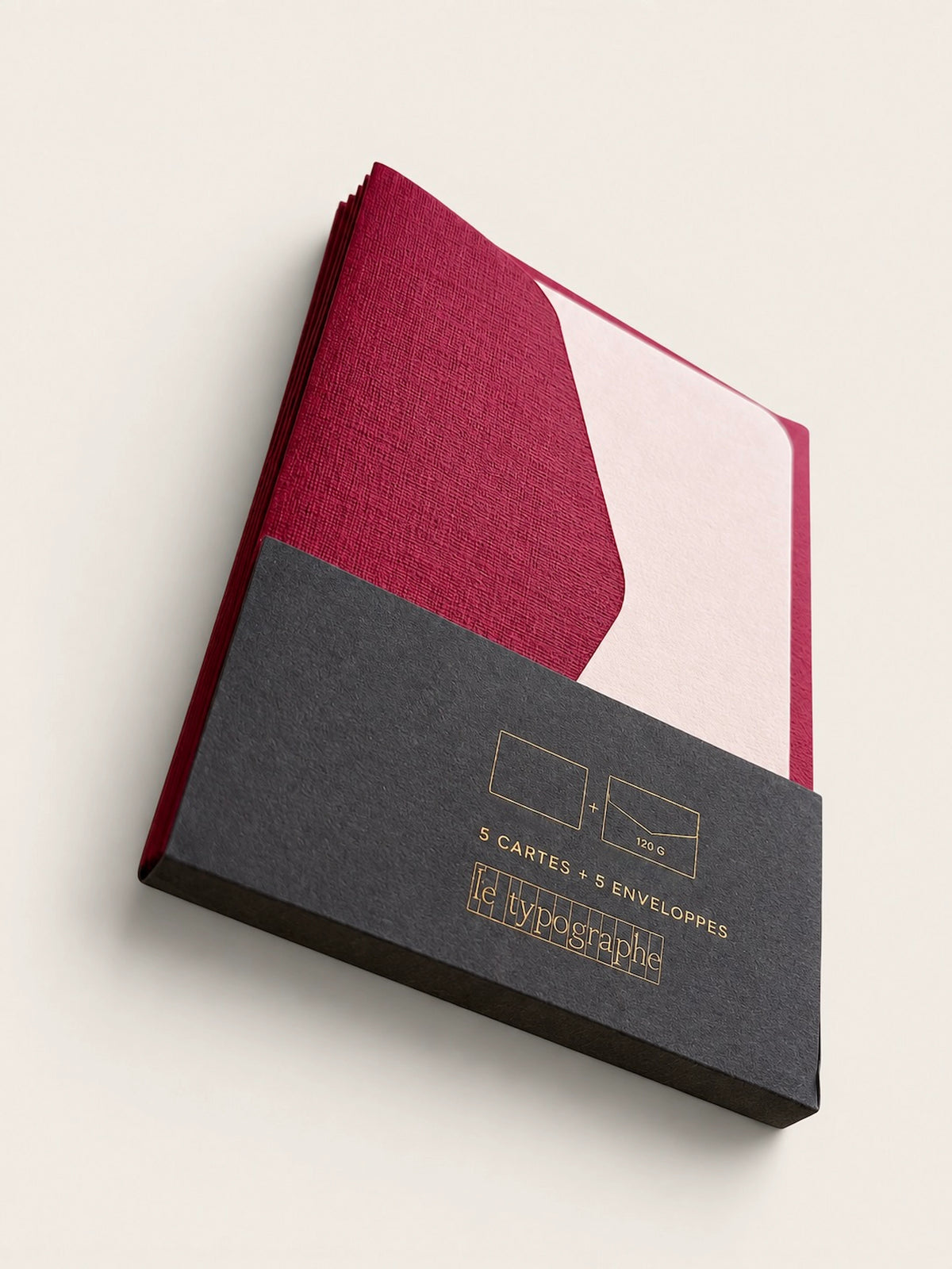 Angled view of Le Typographe burgundy and peach mini cards in charcoal paper sleeve