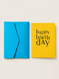 Yellow Happy Birthday letterpress card with rounded corners by Le Typographe, beside its cornflower blue envelope