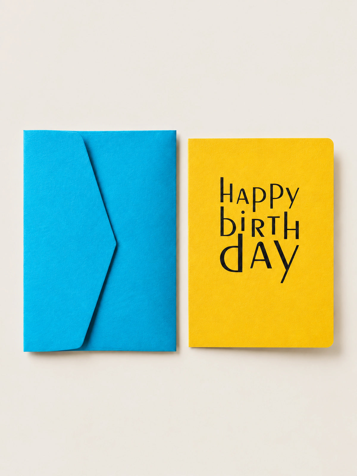 Yellow Happy Birthday letterpress card with rounded corners by Le Typographe, beside its cornflower blue envelope