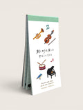 Ourooh Japanese to-do list pad featuring embroidered musical instruments and a blue bird on a green-bound paper block.