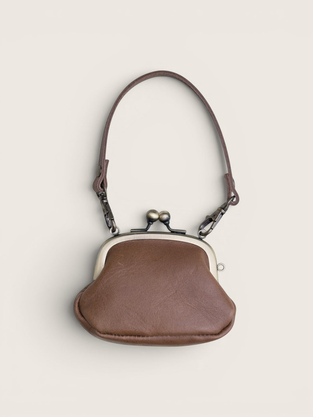 Ourooh Kanmi Japanese leather mini pouch with a brass gamaguchi clasp and adjustable strap in a rounded drop shape.