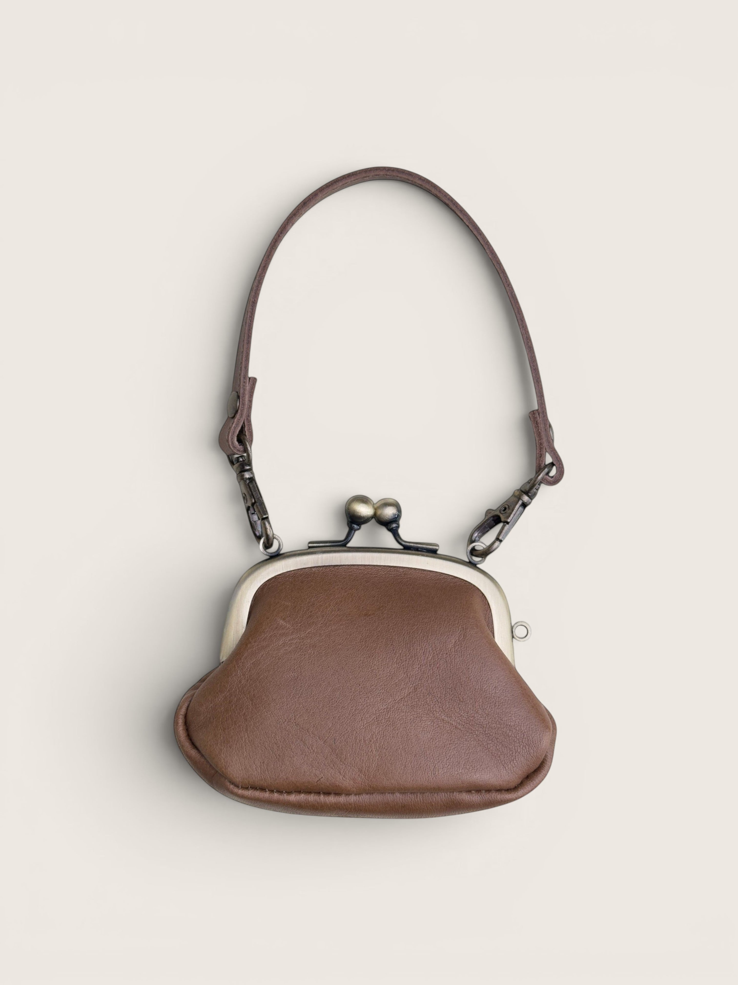 Ourooh Kanmi Japanese leather mini pouch with a brass gamaguchi clasp and adjustable strap in a rounded drop shape.