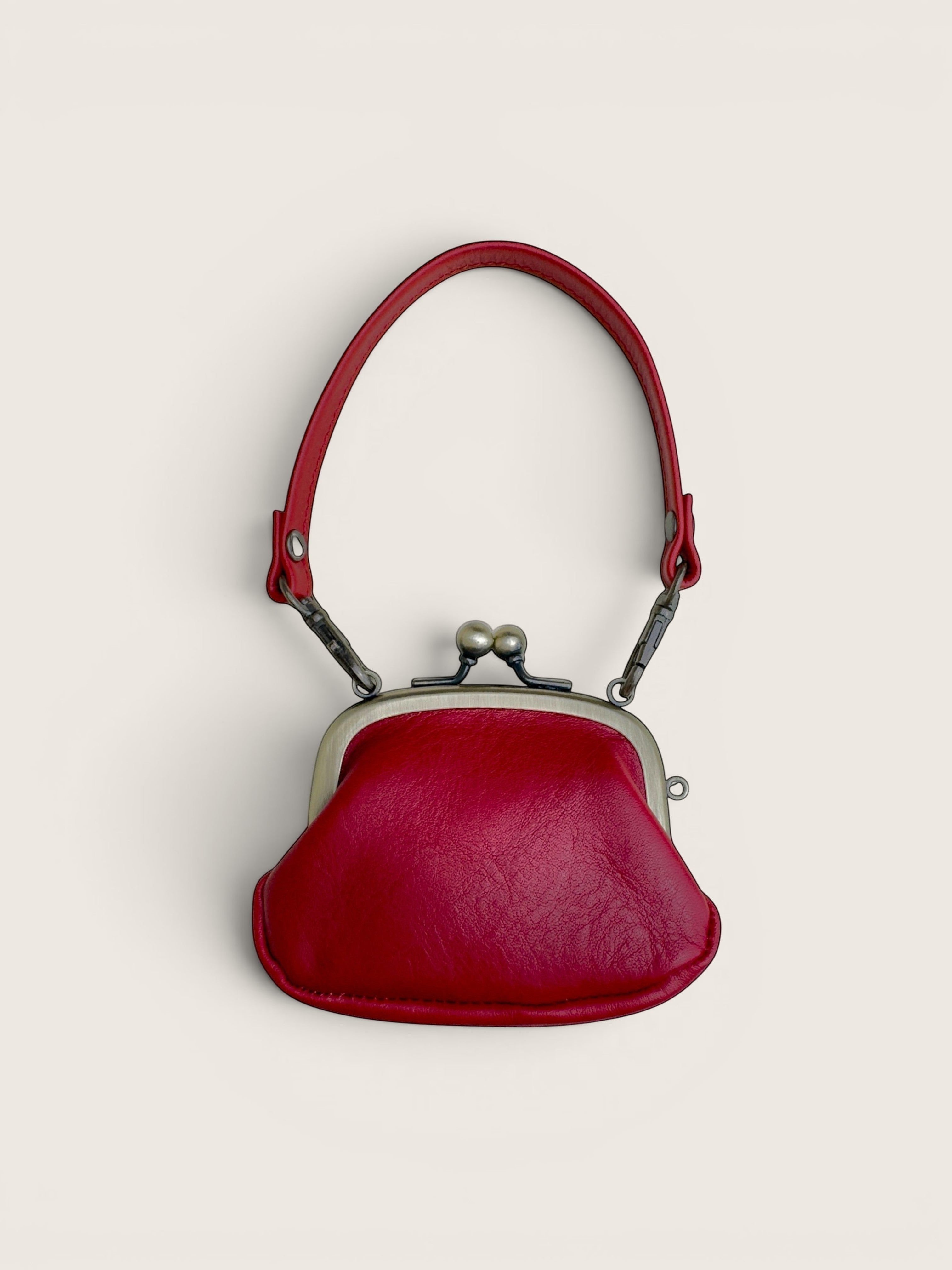 Ourooh Kanmi deep red Japanese cowhide leather mini pouch with a rounded shape, metal gamaguchi clasp, and strap.