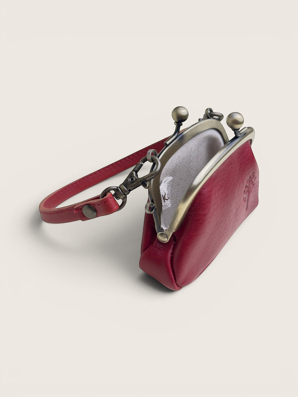 Ourooh Kanmi deep red cowhide leather mini pouch with a brass gamaguchi clasp, adjustable strap, and tree motif.