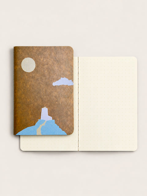 Lighthouse RO-BIKI pocket notebook beside its open ivory dot grid pages and stitched binding